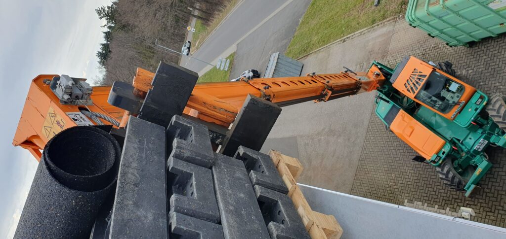 Baumaschinen Bilder. Bagger Fotos Kostenlos. 3 Cramer Manitou Teleskoplader beim Bauzaunfüsse auf Flachdach laden