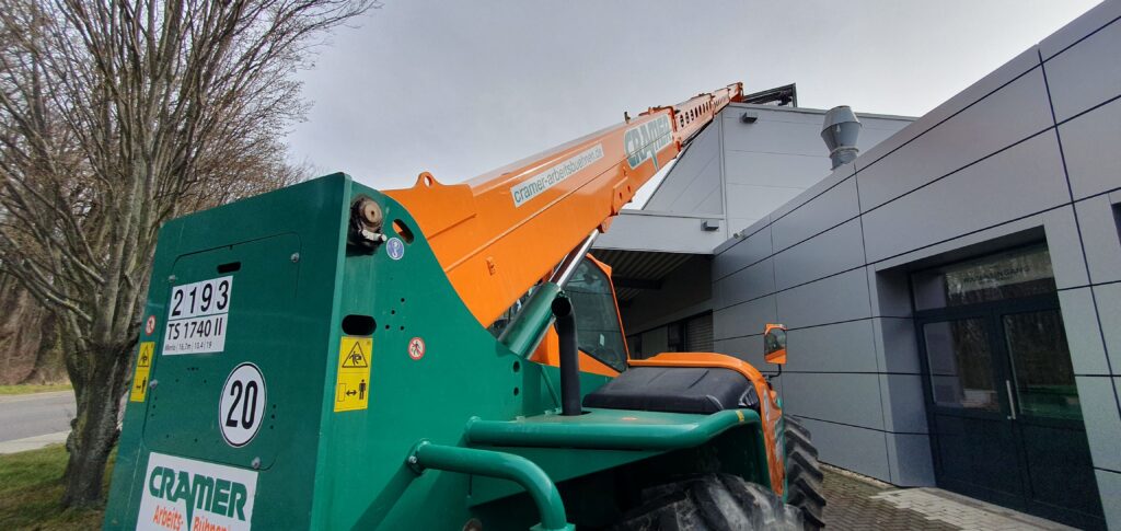 Bauzaun Flachdach Absicherung. PV-Anlagen montieren. PV-Module und Material mit Teleskopstapler TS 1740 II mit starrem Oberwagen auf Dach verladen
